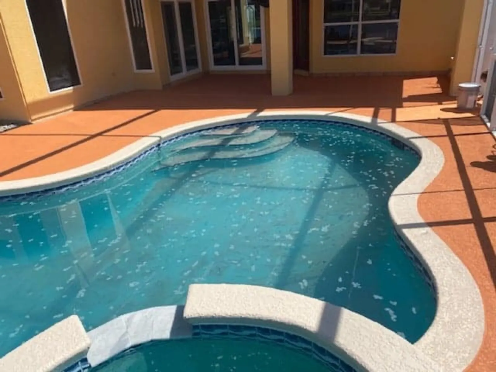 Terracotta colored pool deck resurfacing around a screened pool